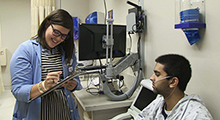 Doctor writing notes while her patient sits in front of her