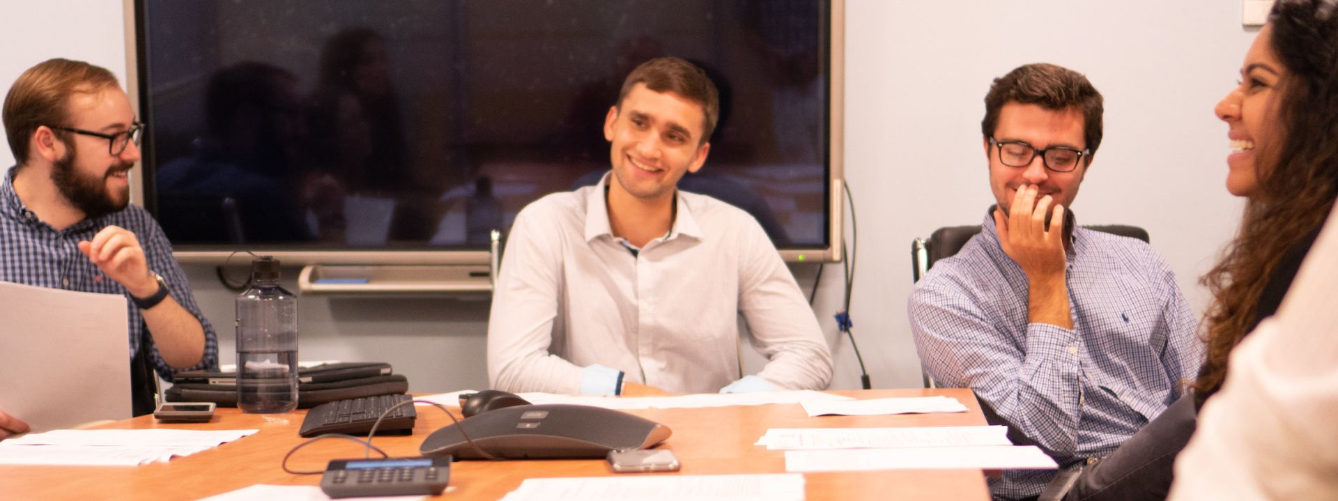 Researchers sitting around a table talking and smiling